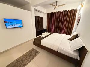 ein Schlafzimmer mit Bett und Flachbildfernseher in der Unterkunft The Aura Rooms, Calangute in Calangute