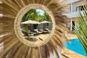a mirror view of a pool with chairs and umbrellas at Shirley Boutique Hotel in Kiwengwa
