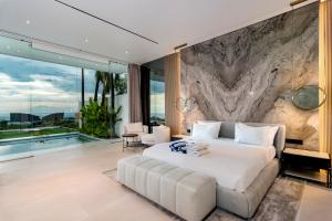 a bedroom with a large white bed and a stone wall at Sky Star Uluwatu in Uluwatu +127 photos