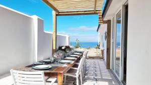 a long wooden table on the balcony of a house at Ashore - Beachfront Paradise in St. Helena Bay