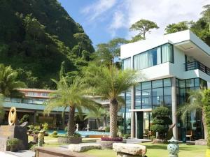 un grand bâtiment blanc avec des palmiers devant dans l'établissement Phi Phi Nice Beach Hotel Hip, sur les Îles Phi Phi