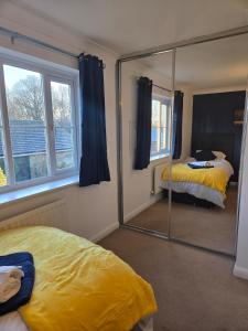 Cette chambre comprend deux lits et un grand miroir. dans l'établissement Duxford Haven, à Duxford