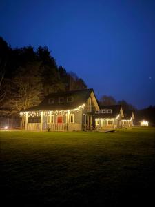 ein nachts beleuchtetes Haus mit Lichtern in der Unterkunft Domy nad Strugą - jacuzzi, las, wieś, rowery, kajaki 