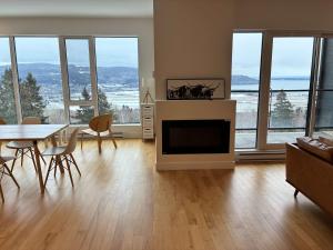een woonkamer met een open haard en een tafel en stoelen bij 309 - Luxury Condo - Spectacular View & Pool in Baie-Saint-Paul