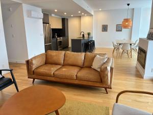 een woonkamer met een bruine bank en een keuken bij 309 - Luxury Condo - Spectacular View & Pool in Baie-Saint-Paul