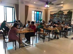 a group of people sitting at tables in a restaurant at AVS Nội Bài Hotel in Sóc Sơn