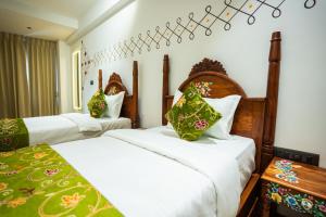 a bedroom with two beds with green and white sheets at Hotel Indiana Hitech City in Hyderabad