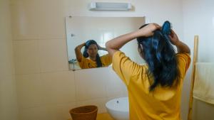 a woman brushing her hair in front of a mirror at Maison Hely Tiana in Antananarivo