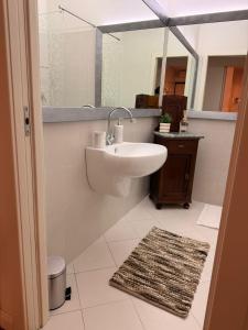 een badkamer met een wastafel, een spiegel en een tapijt bij Rose e Frutta - Silver Moon in Monfalcone +14 foto's