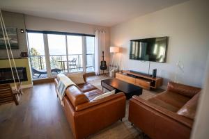 een woonkamer met 2 banken en een televisie bij 311 - Luxury Condo The 5 Senses - View Pool & EV in Baie-Saint-Paul