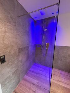 een badkamer met een douche met paarse verlichting bij AurAlpin Apartments in Cadipietra