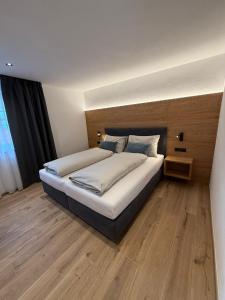 een slaapkamer met een groot bed met een houten vloer bij AurAlpin Apartments in Cadipietra