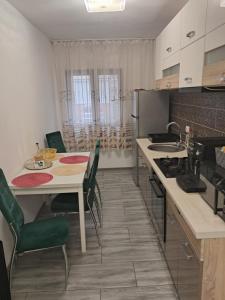 una cucina con tavolo, sedie e frigorifero di Apartament NECTARIA a Băile Herculane