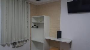 a living room with a tv and a white curtain at Hotel Recanto das Perdizes in São Paulo