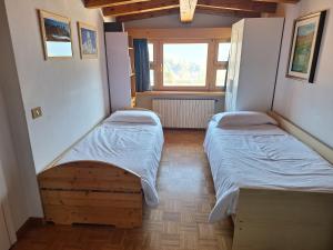 zwei Betten in einem kleinen Zimmer mit Fenster in der Unterkunft Camera con vista in Calalzo