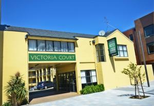 a yellow building with a sign for a vctoria court at Victoria Court Motor Lodge - Free Parking in Wellington