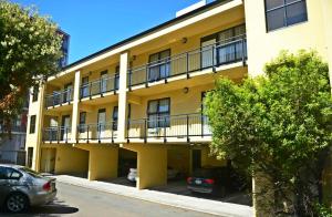 a yellow building with cars parked in front of it at Victoria Court Motor Lodge in Wellington