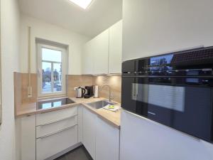 a kitchen with white cabinets and a black appliance at Ferienwohnung KüstenSAND in Norden