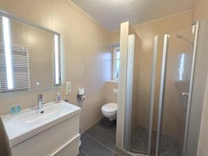 a bathroom with a sink and a toilet and a shower at Ferienwohnung KüstenSAND in Norden +16 photos