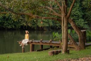 a woman sitting on a dock near a body of water at Comsaed River Kwai Resort in Kanchanaburi City