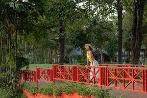 a woman walking on a red bridge at Comsaed River Kwai Resort in Kanchanaburi City