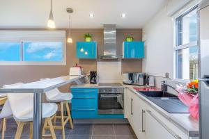 a kitchen with blue cabinets and a counter at Villa Yana Bretagne Piscine Intérieure partagée et Spa Privatif 100m de la Plage in Sibiril