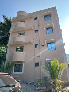 a pink building with round windows and palm trees at Azara Watamu in Watamu