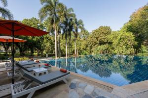 een zwembad met stoelen en een parasol naast een zwembad bij Comsaed River Kwai Resort in Kanchanaburi +63 foto's
