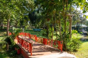 een rode brug in een park met bomen en water bij Comsaed River Kwai Resort in Kanchanaburi