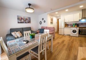 a kitchen and living room with a table and a couch at YourHouse Apartamentos Andasol 1D in Chipiona