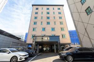 a tall building with cars parked in a parking lot at 호텔휴 in Namch'unch'ŏn-yŏk