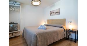 a bedroom with a bed with a blue blanket on it at YourHouse Apartamentos Andasol 1 I in Chipiona