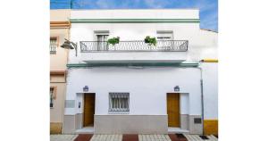 a white building with a balcony with two plants on it at YourHouse Apartamentos Andasol 1 I in Chipiona