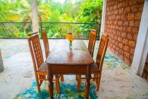 a table with three chairs and a vase with flowers on it at Lucky Rest in Beruwala