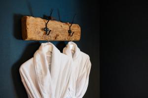 a white robe hanging on a wall with a wooden holder at Boutique vakantiehuis Het Stalhuys in Reeuwijk