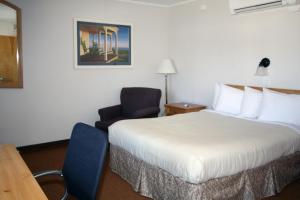 MachiasにあるThe Bluebird Motel Maineのベッドと椅子付きのホテルルーム