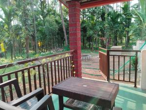 eine Veranda mit einem Holztisch und Stühlen auf dem Balkon in der Unterkunft Hegde Farmstay in Udupi