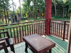 einen Balkon mit einem Holztisch und einem Holzzaun in der Unterkunft Hegde Farmstay in Udupi + 16 Fotos