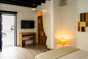a bedroom with a bed and a desk and a television at La Geria Suites in Yaiza