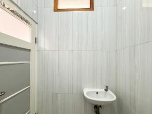 un bagno bianco con lavandino e doccia di Sofia Residence Syariah Mitra RedDoorz a Malang