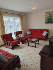 a living room with red couches and chairs at VSA SELF CATERING unit 1 in Newcastle