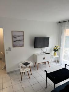 a living room with a tv on a white wall at Mon Appart avec Terrasse et Piscine in Roquebrune-Cap-Martin