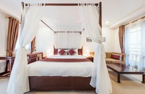 Schlafzimmer mit einem großen Bett und weißen Vorhängen in der Unterkunft La Dolce Vita Hotel in Hanoi