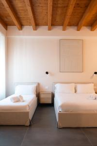 2 letti in una camera con pareti bianche e soffitti in legno di Tower Studio Triple Suite - Bernina Experience a Tirano