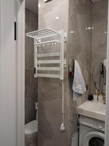 a bathroom with a toilet and a sink and a washing machine at Rams city квартира in Zhezdi +1 photo