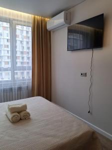 a bedroom with a bed with a tv on the wall at Rams city квартира in Zhezdi