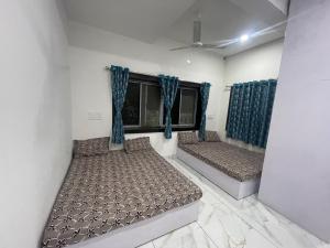 twee bedden in een kamer met blauwe gordijnen bij Jogi Homestay in Dwarka