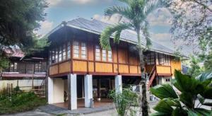a house with a palm tree in front of it at Hotel O Mountain View Homestay in Tomohon