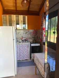 a kitchen with a white refrigerator and a stove at Recanto Boa Vista - Chalé 1 in São Thomé das Letras