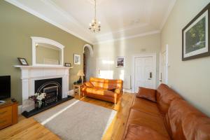 a living room with a leather couch and a fireplace at Cleish Apartment in Edinburgh